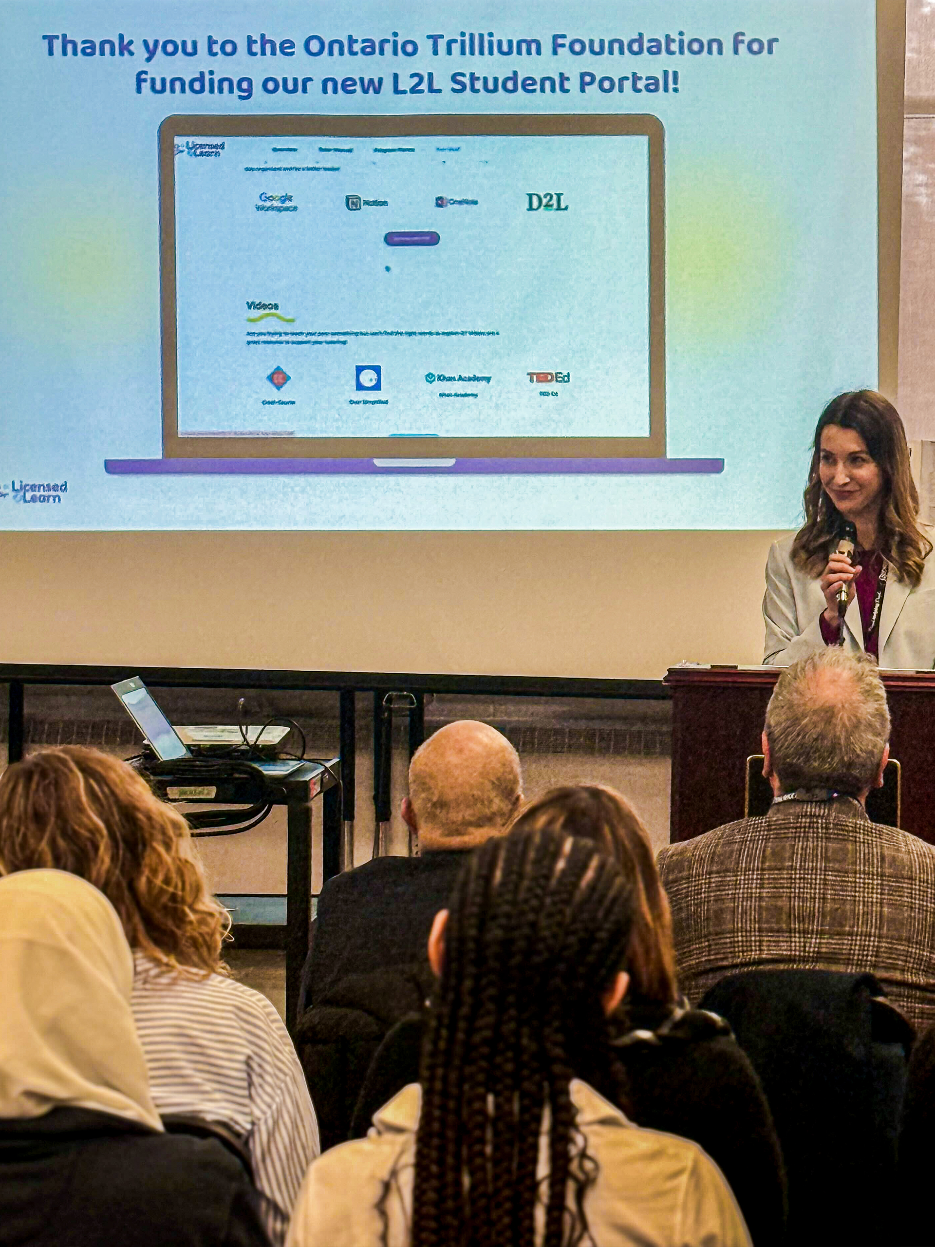 A woman confidently presents at a conference, engaging the audience with her insights and expertise.