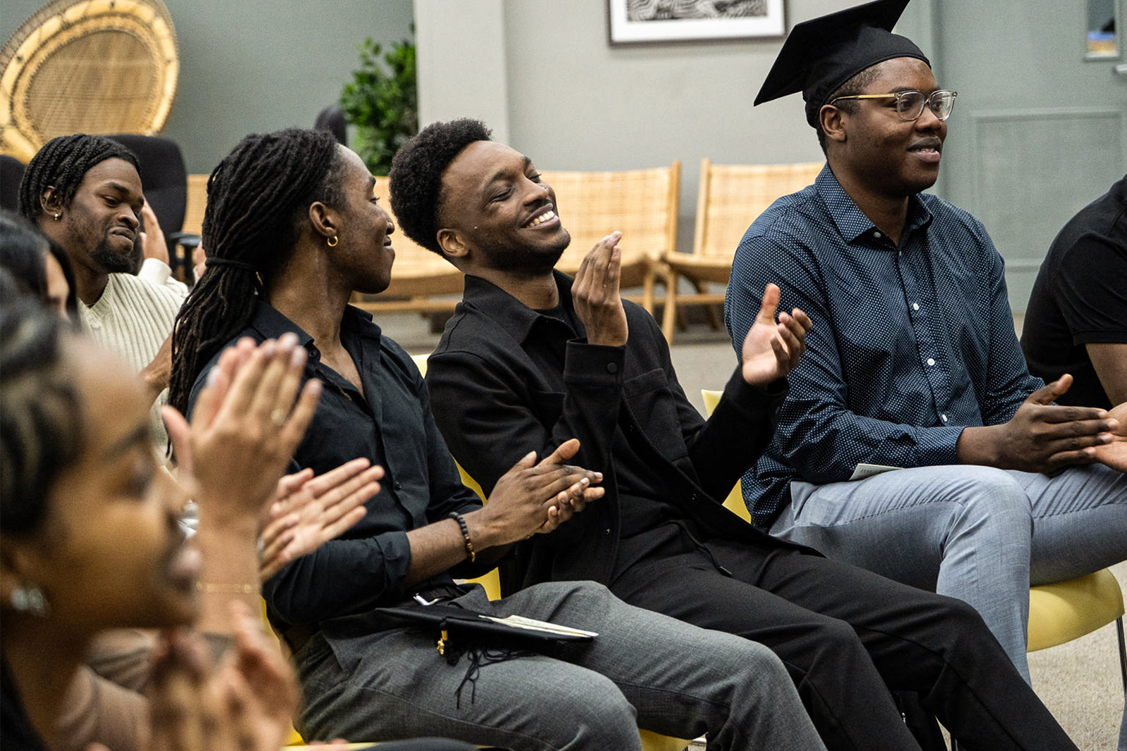 A diverse group of people seated, applauding enthusiastically in a formal setting.