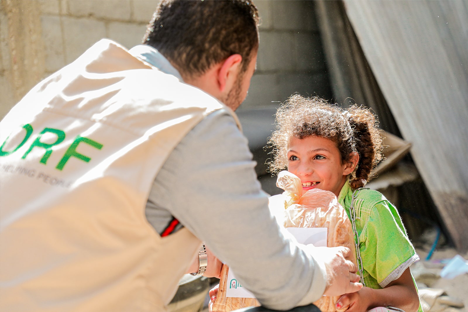 A man graciously hands a child a bag of food, symbolizing kindness and support in a moment of sharing.