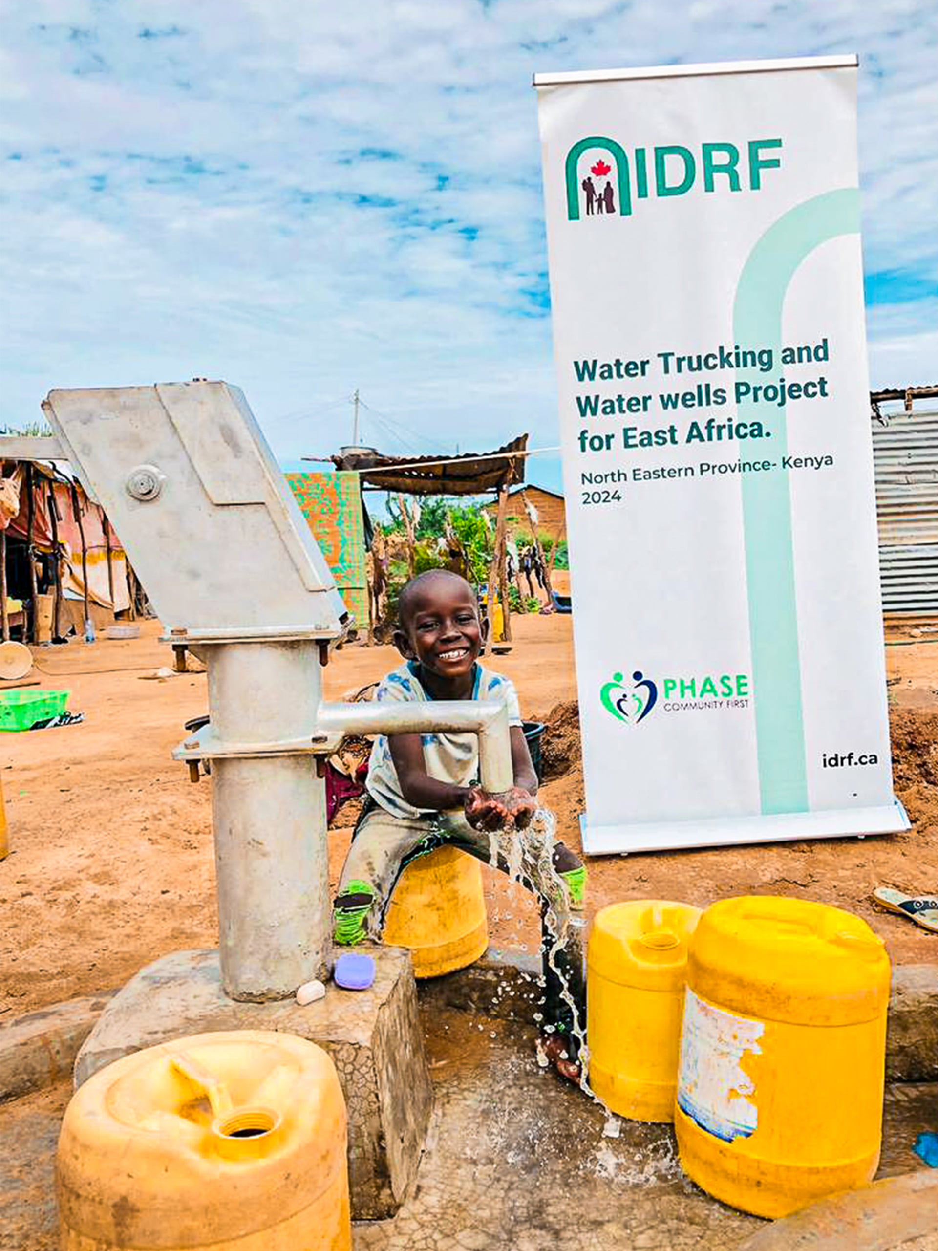 A child sits on a water pump beside a sign about water tracking and budgeting, promoting water conservation awareness.