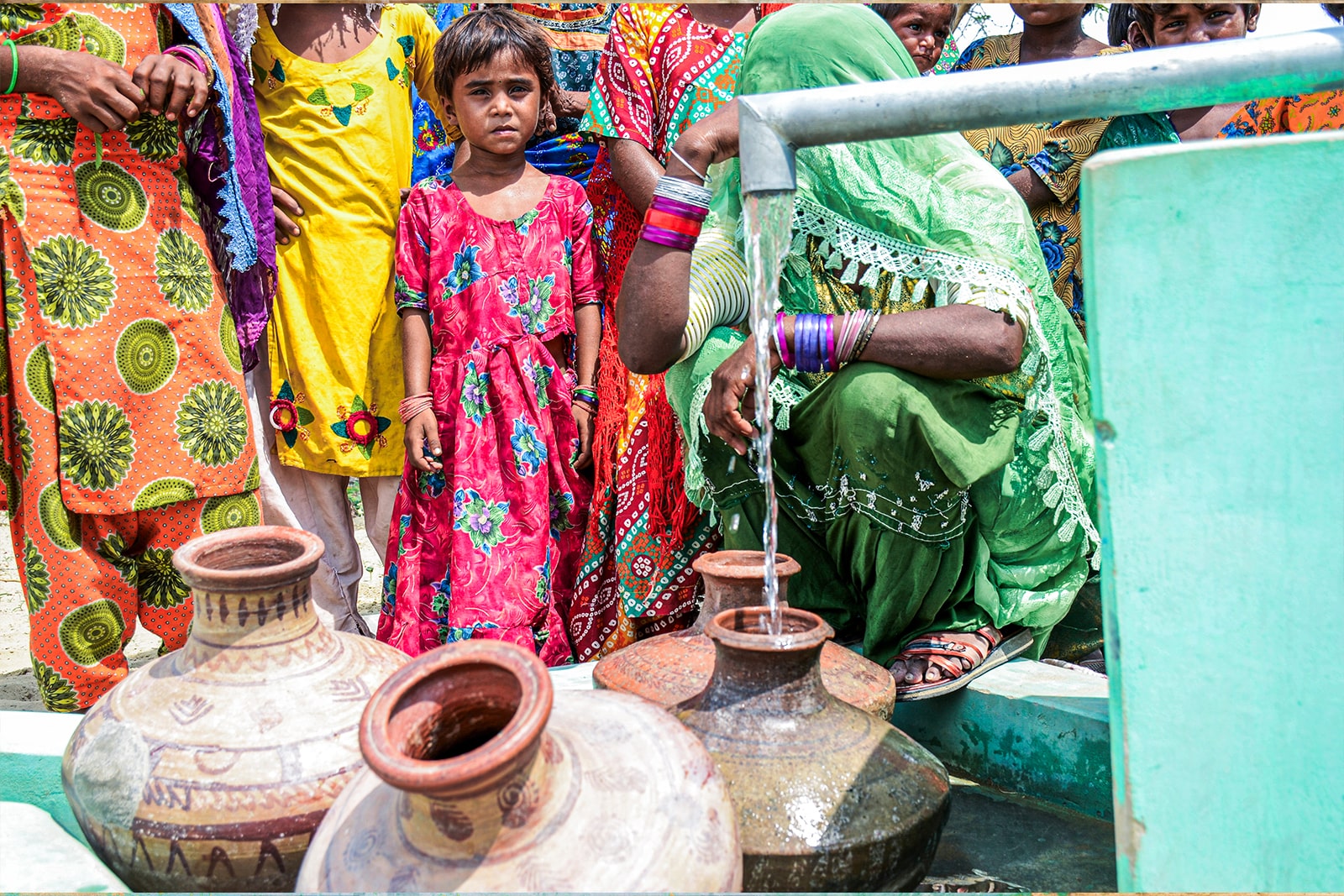 A woman gracefully draws water from a traditional well, embodying strength and resilience in her daily task.