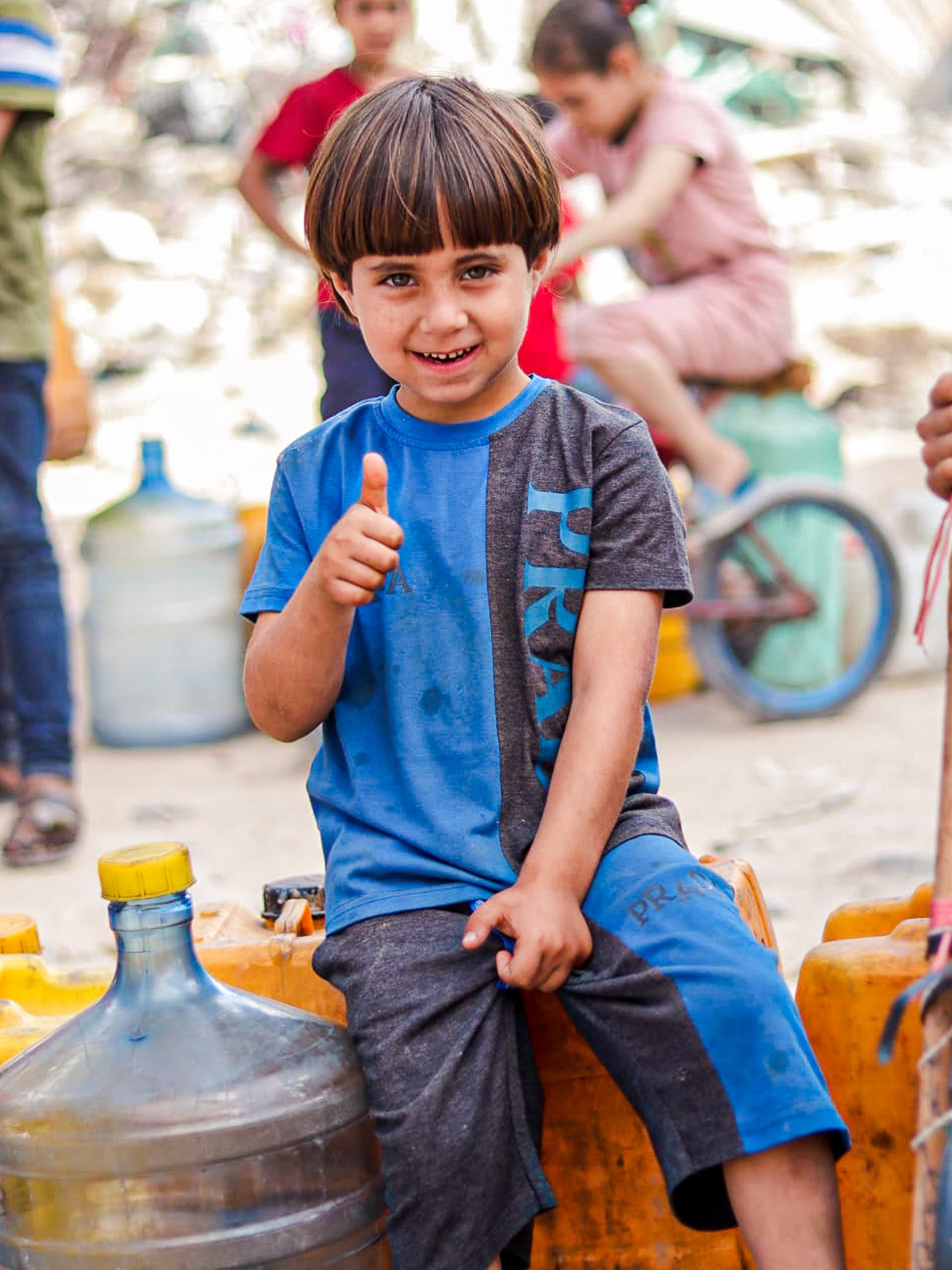 A young boy sits on a bench, smiling and giving a thumbs up, exuding confidence and positivity.