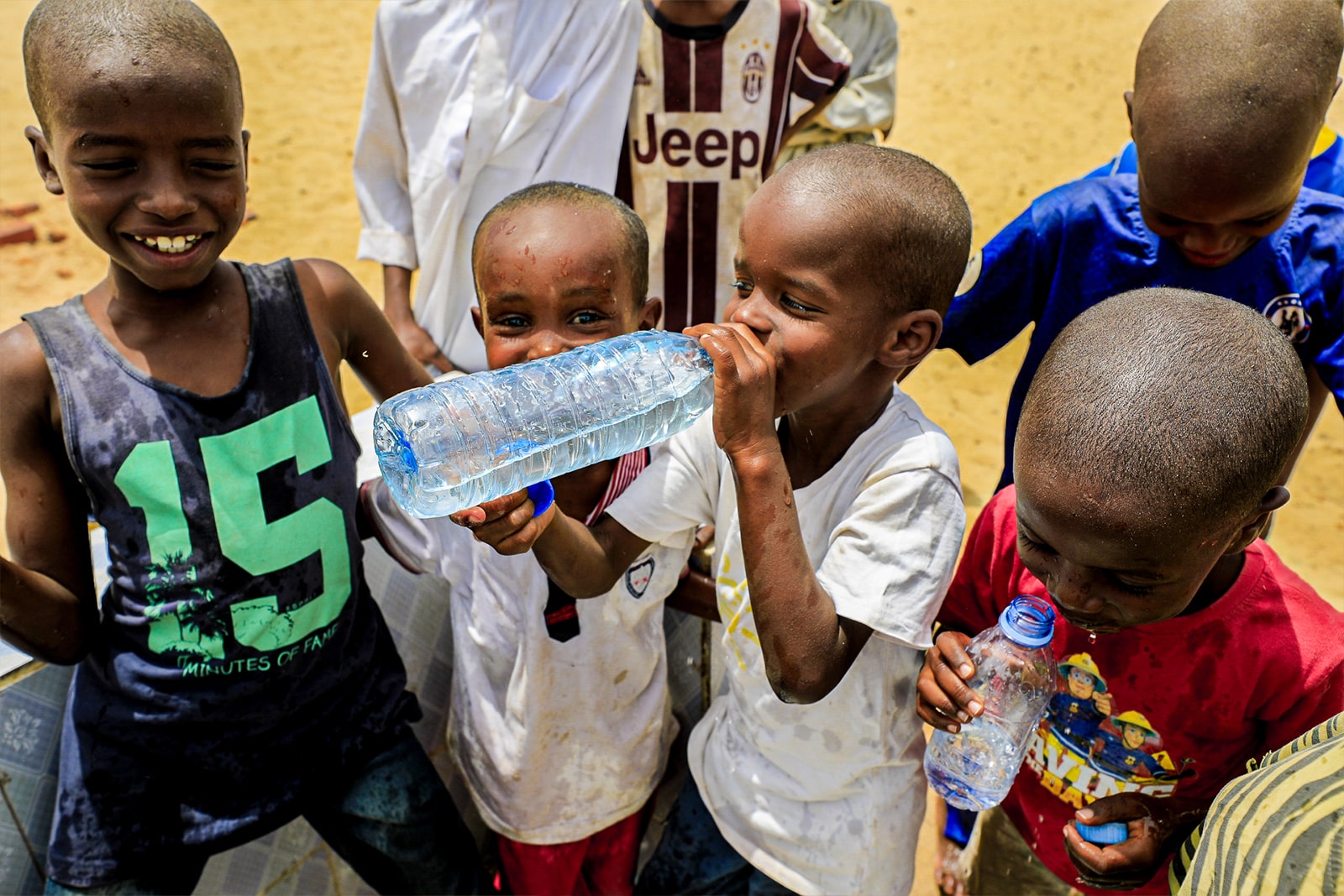 Children in Africa joyfully drinking clean water from a communal source, highlighting the importance of access to safe water.