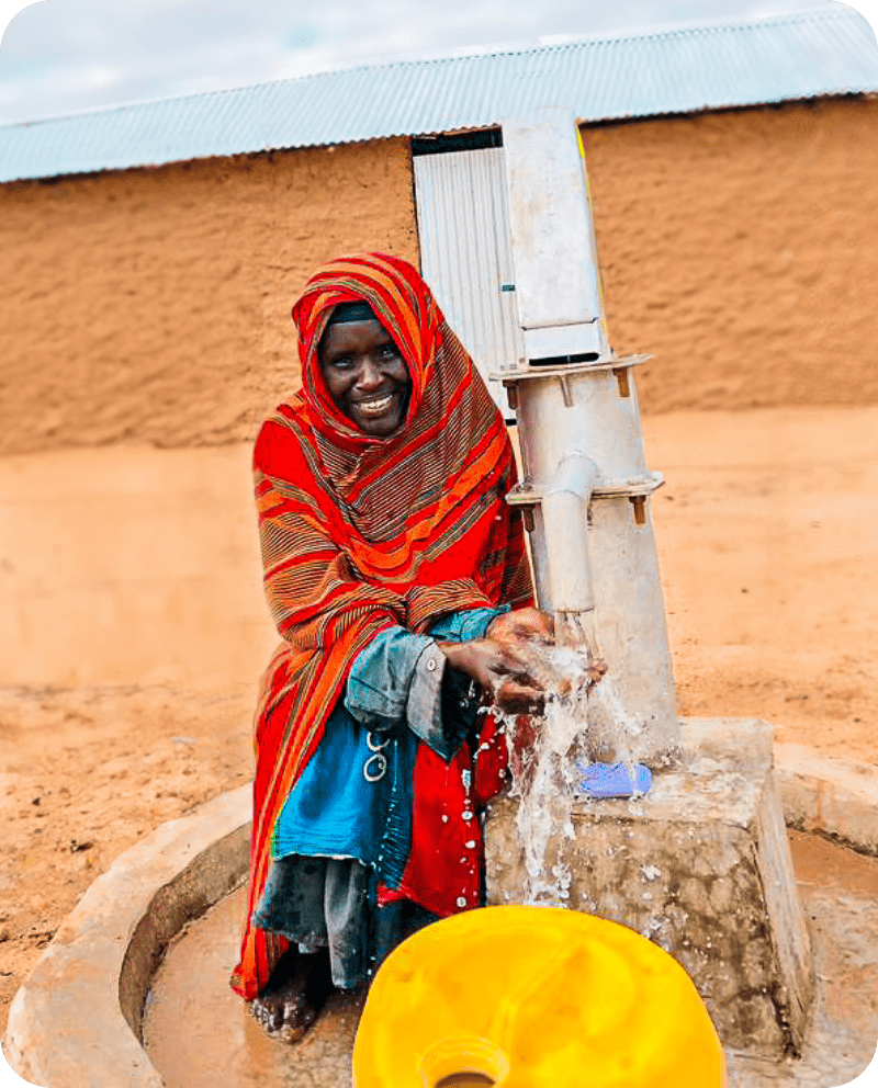 A woman in a red scarf sits gracefully on a water pump, embodying strength and resilience in her surroundings.