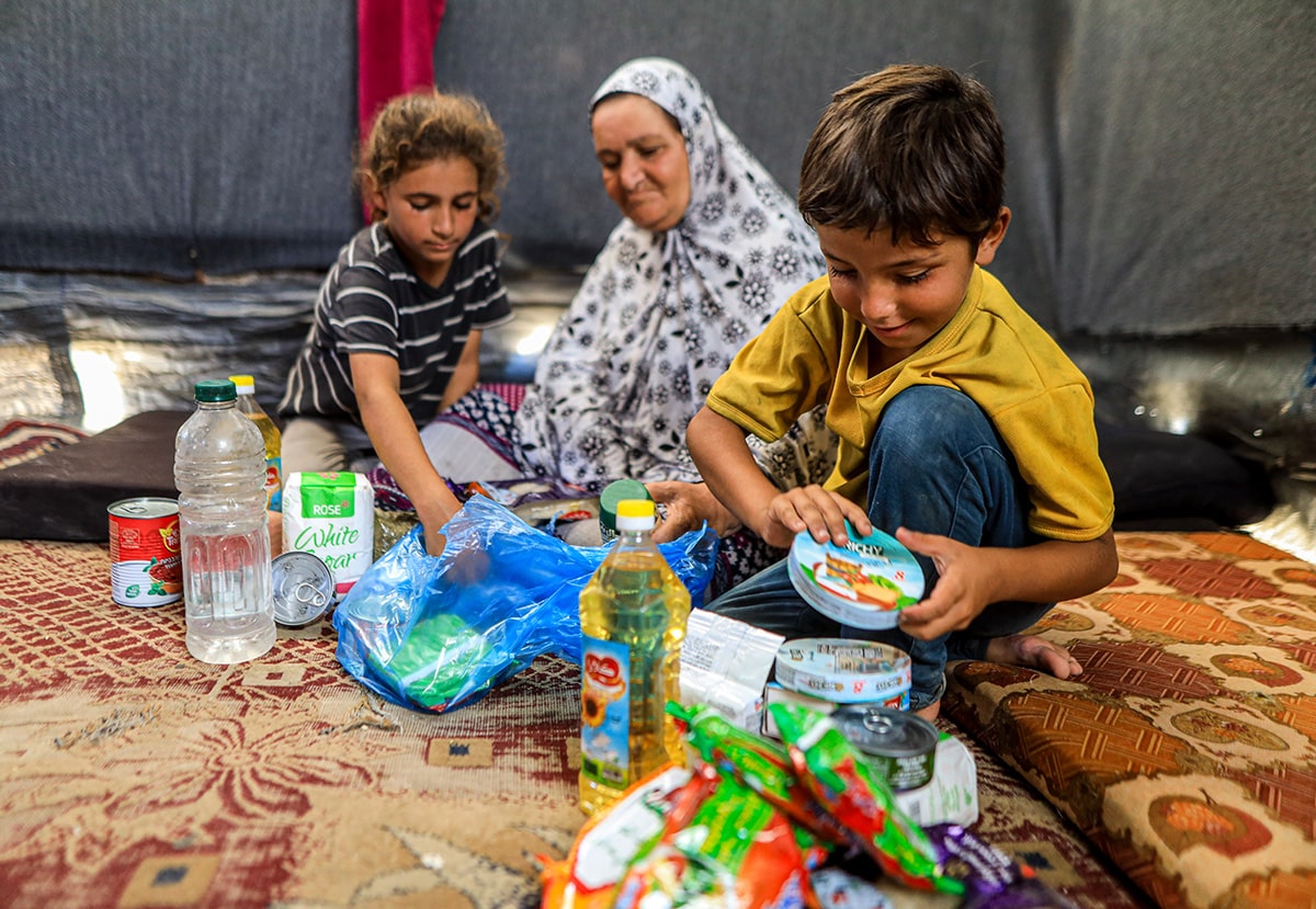 A family sits together in a tent in Aleppo, showcasing resilience amidst challenging circumstances.