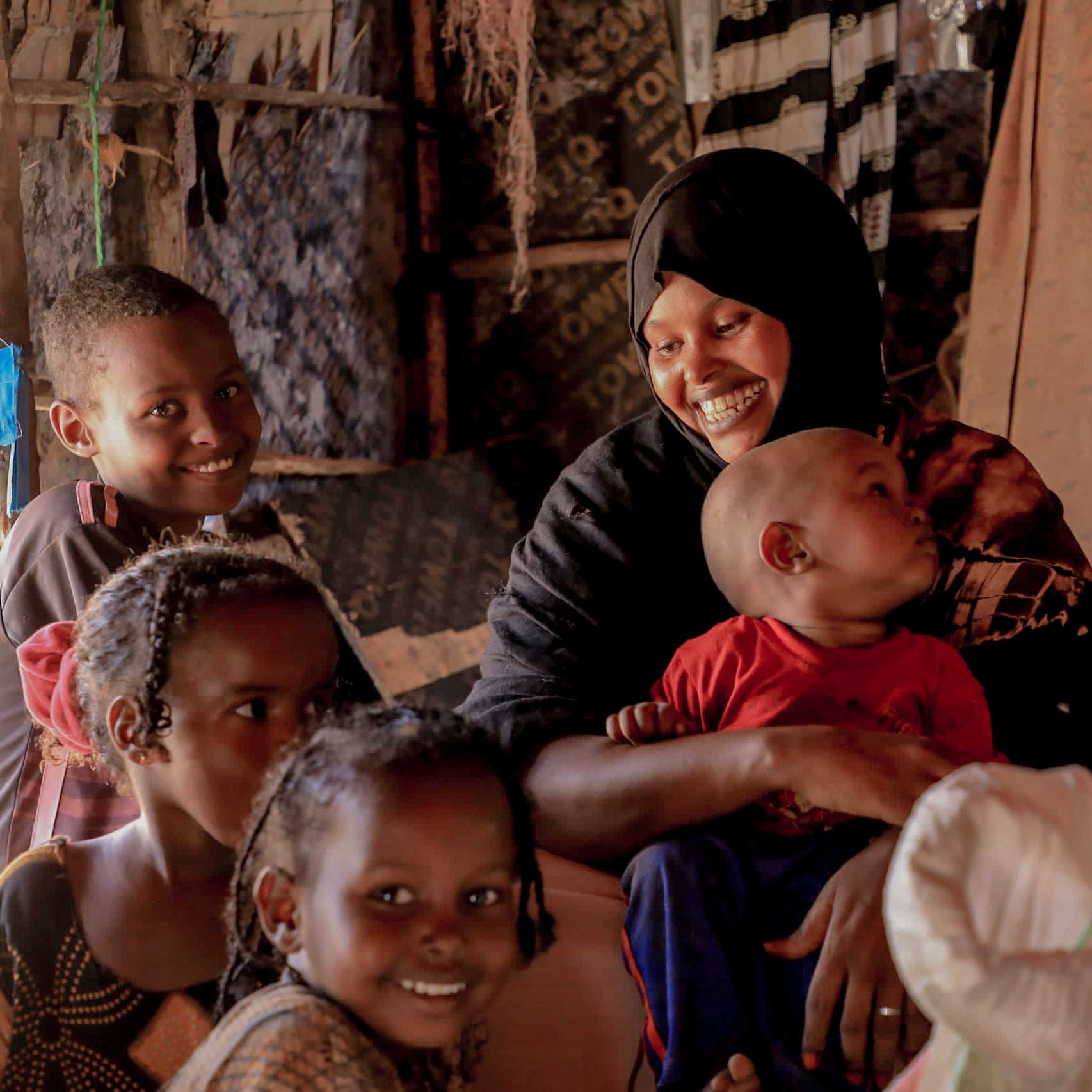 A smiling woman gently cradles a baby in her arms, showcasing a warm and loving moment between them.