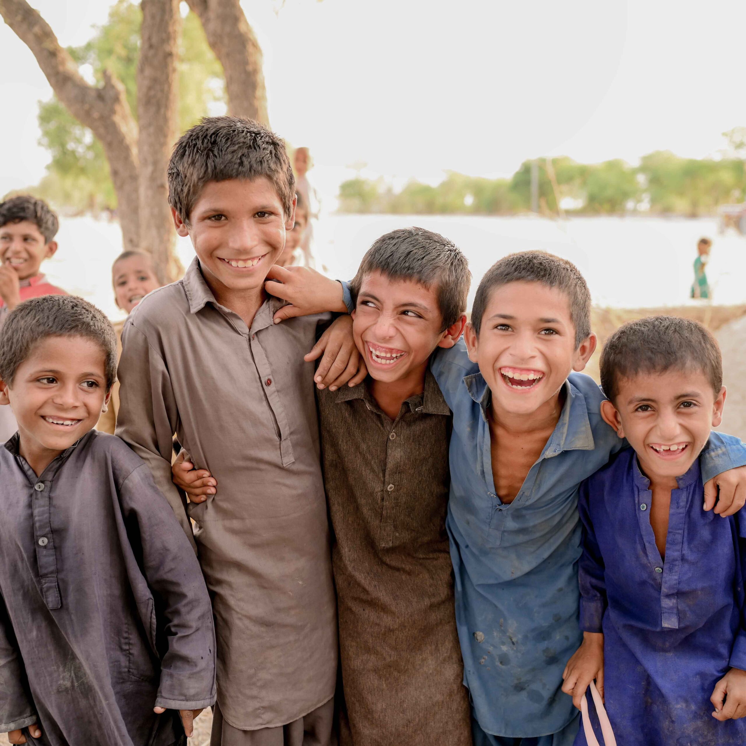 A group of boys standing together, smiling and enjoying each other's company outdoors.